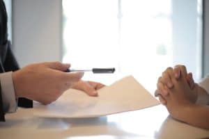 Pourquoi souscrire une assurance est essentiel pour protéger votre quotidien ? Close-up of a contract signing with hands over documents. Professional business interaction.