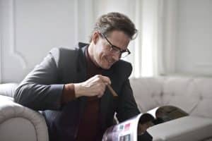 Finances : ces placements faciles incroyablement rentables qui vont vous rendre riches Smiling rich gentleman wearing classy suit and stylish eyeglasses sitting with cigar on leather sofa in luxury living room and reading magazine