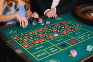 Découvrez le secret des casinos en ligne : les bonnes pratiques à adopter pour gagner Captivating scene of a casino roulette table with gamblers placing their bets.