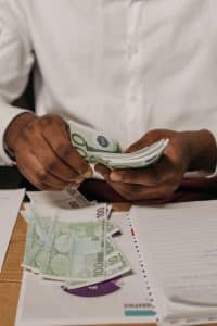 Cette nouvelle aide augmente vos revenus : profitez de ce bonus exceptionnel avant la date limite Close-up of hands counting Euro bills with paperwork on a desk.
