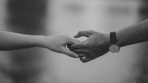 Surmonter un chagrin d’amour : Comment être prêt pour un nouveau départ Monochrome image of two hands holding, symbolizing love and connection.