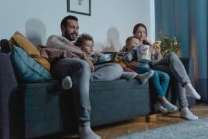 L’animateur Arthur animera un nouveau numéro de « Vendredi tout est permis » le 31 janvier A family of four enjoys a cozy evening on the sofa, bonding over movies and popcorn indoors.
