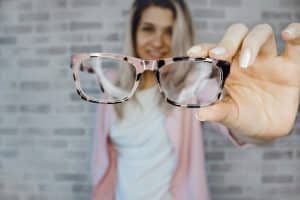 Comment bien choisir ses lunettes de vue pour allier confort, style et efficacité visuelle ?Le titre à définir par l’éditeur Young woman with blonde hair holding eyeglasses indoors, focusing on vision aid.