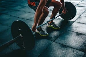 Sport : entre culture populaire et instrument du capital Man performing a deadlift exercise in a gym, demonstrating strength and fitness.