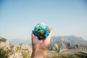 Les top destinations incontournables pour voyager en décembre Hand holding a globe against a mountain background symbolizing travel and exploration.