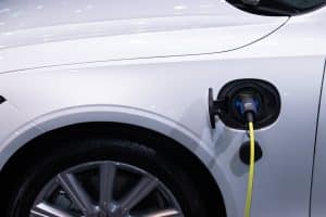 Voiture électrique : un choix rentable pour votre budget au quotidien ? A white electric car is plugged in for charging, close-up view of the charging port.